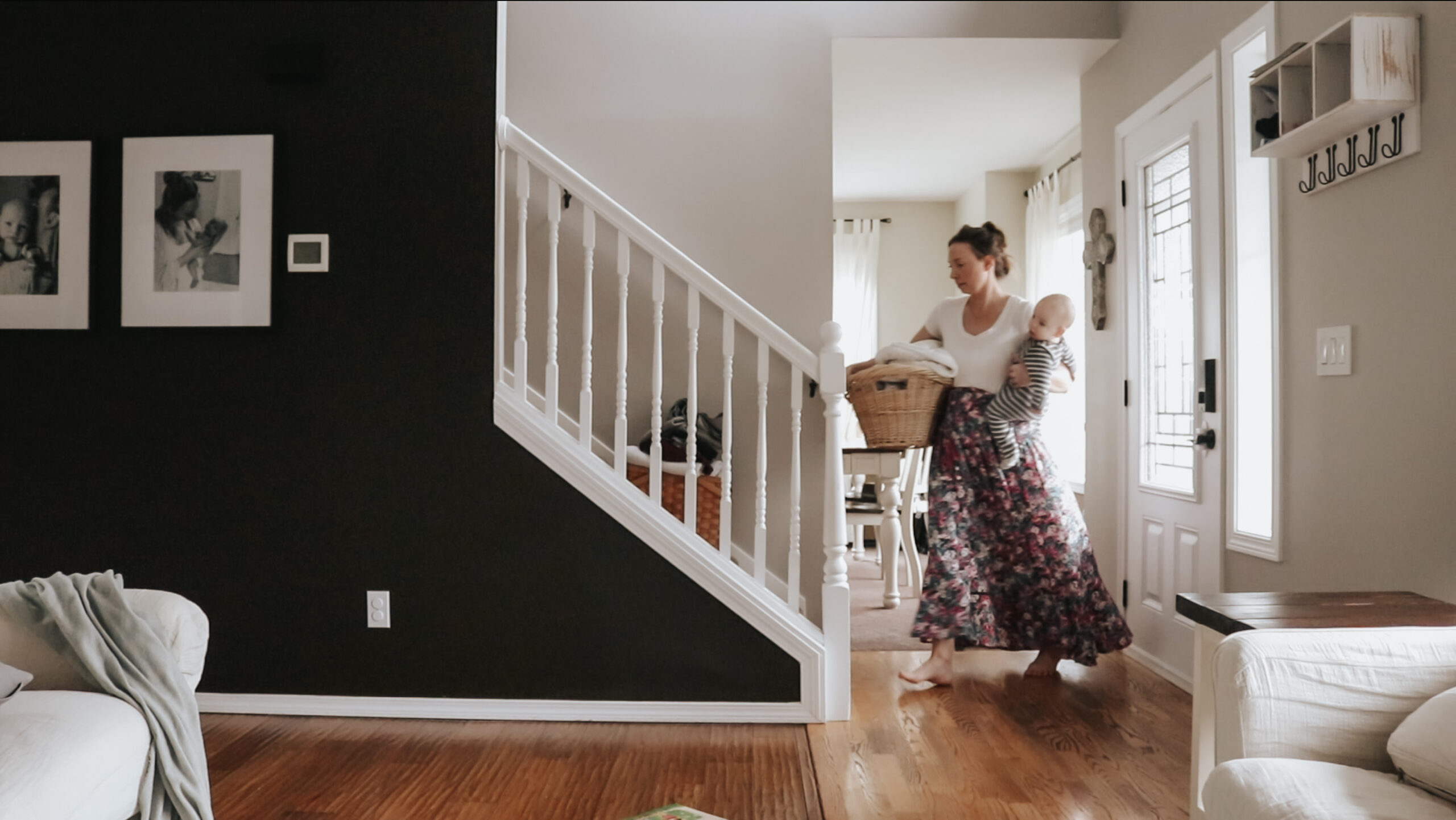 Christian mom carries a laundry basket up the stairs while holding a baby on one hip